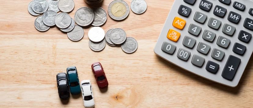 Monede, calculator și mașinuțe așezate pe un birou