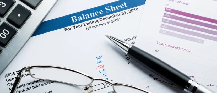 Calculator, ochelari și pix peste un raport financiar cu grafice